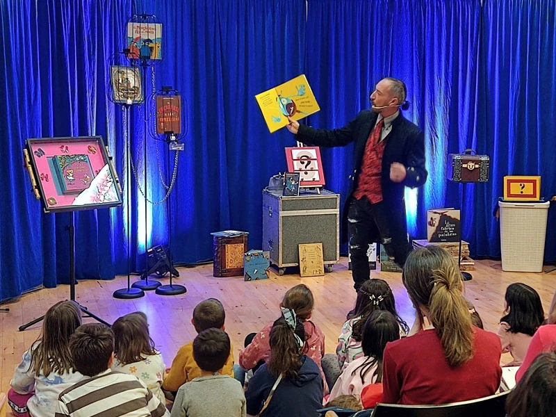 Pedro III sostiene un libro en alto ante los niños sentados en el suelo